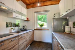a kitchen with wooden cabinets and a window at Domki Potok - Noclegi Bieszczady in Stefkowa