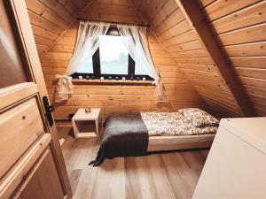 a bedroom with a bed in a wooden cabin at Slope House (Domek na Skarpie) Lipowa in Lipowa