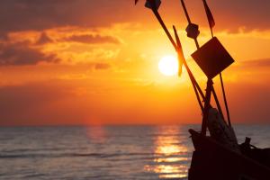 una puesta de sol en la playa con un barco en Willa Rawia, en Rewal