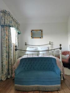 1 dormitorio con 1 cama y 1 sofá azul en The Coach House en Cholderton