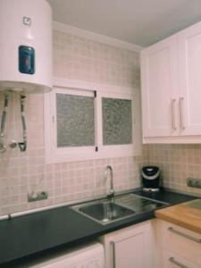 eine Küche mit Spüle und weißen Schränken in der Unterkunft Apartamento Sissi in Nerja