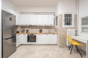 a kitchen with white cabinets and a yellow chair at Victoria Secret Apartments in Athens