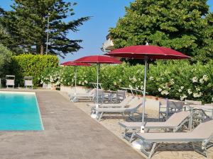 - un groupe de chaises longues et de parasols à côté de la piscine dans l'établissement Le Bisceglie, à Albanella