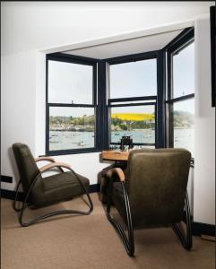 een kamer met 2 stoelen, een tafel en ramen bij CAPTAINS LOFT in Falmouth