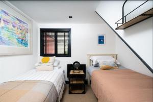 two beds in a room with white walls at CAPTAINS LOFT in Falmouth