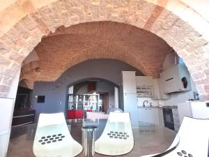 una cocina con 2 sillas blancas y un arco en Assisi Garden Suite en Assisi