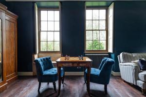 Habitación con paredes azules, mesa y sillas. en Topside House - Beautiful 7 bedroom house with hottub wifi and parking near Bath Wells Frome, en Oakhill