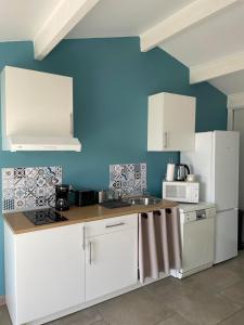 a kitchen with white cabinets and a blue wall at « La Parenthèse » gîte en Camargue in Arles