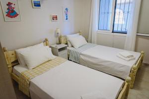 two beds in a small room with a window at Villa Angelos in Ermioni