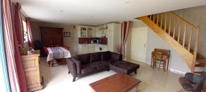 a living room with a brown couch and a kitchen at Gite Couesnon in Roz-sur-Couesnon