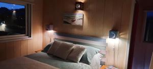 Un dormitorio con una cama con dos luces. en LAS ESCAMADAS ecocottage, en Punta del Diablo