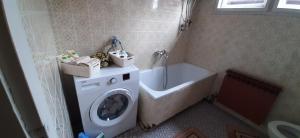 a bathroom with a washing machine and a tub at Apartman Nina in Visoko