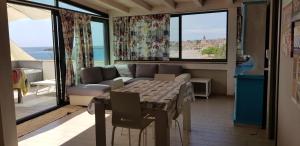 ein Wohnzimmer mit einem Sofa, einem Tisch und Fenstern in der Unterkunft Santanna Penthouse - Fondachello-apartments com in Riposto