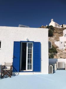 a blue shutter on a white building with a bench at Maria's View in Ios Chora