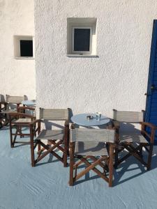 a group of tables and chairs next to a wall at Maria's View in Ios Chora