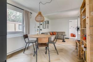uma cozinha e sala de jantar com mesa e cadeiras em Cosy 4 pers chalet midden in bos op de Veluwe em Doornspijk