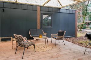 eine Terrasse mit Stühlen, einem Tisch und einem Grill in der Unterkunft Cosy 4 pers chalet midden in bos op de Veluwe in Doornspijk