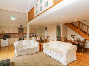 a living room with two white chairs and a kitchen at Meader Barn in Marytavy