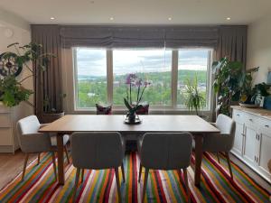 uma mesa de jantar com cadeiras e uma grande janela em Modern and Cozy home with an outstanding view em Asker