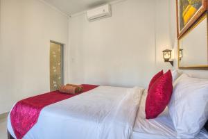 een slaapkamer met een wit bed met rode kussens bij L Degus Hostel in Nusa Penida