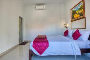 een slaapkamer met een groot wit bed met rode kussens bij L Degus Hostel in Nusa Penida