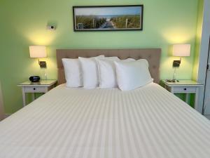 una camera da letto con un grande letto con cuscini bianchi di Dragonfly Guest House a Ogunquit