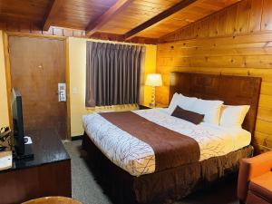 a bedroom with a bed and a desk with a television at Apple Inn Motel in Chelan