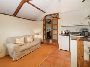 a living room with a couch and a kitchen at Nestling Barn in Marytavy
