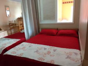 a bedroom with two beds with red sheets and a window at Menina da Lua in Rio das Ostras