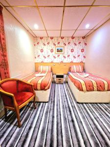a room with two beds and a chair and a desk at The Albany Hotel in Blackpool