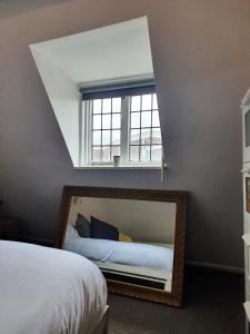 a bedroom with a mirror and a window at Grade I listed luxury apartment in Hertfordshire in Ware