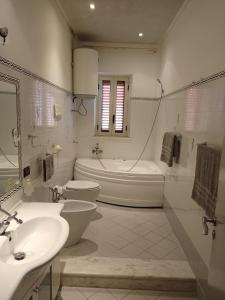 een witte badkamer met 2 wastafels, een bad en een toilet bij Laerte & Dafne Holiday in Trappeto