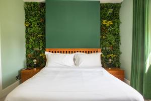 a bed with a white bedspread and a green plant at Holm House Hotel in Cardiff
