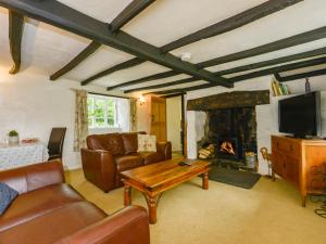 Little Week Cottage في Bridestowe: غرفة معيشة مع أريكة ومدفأة