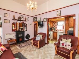 uma sala de estar com duas cadeiras e uma lareira em Brendan's Cottage em Ilha de Valentia