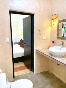 a bathroom with a sink and a toilet and a bed at Hotel Green River in Izamal