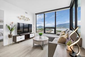 a living room with a couch and a tv and large windows at Brand New Luxury Downtown Near the Beach #16 in Kelowna