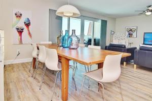 uma sala de jantar com uma mesa de madeira e cadeiras brancas em Holiday Villas II 413 em Clearwater Beach