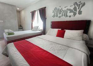 um quarto com 2 camas com lençóis vermelhos e brancos em RUMAH KOPI SYARIAH HOTEL em Bandar Lampung