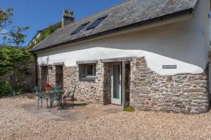 a stone cottage with a table and chairs outside at Cola's Tonne in Malborough