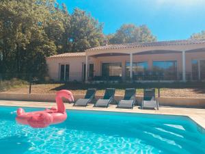 un cygne rose dans une piscine en face d'une maison dans l'établissement Cahors 10 personnes piscine Villa Carpe Diem certifiée 4 étoiles, à Arcambal