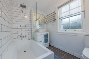 a white bathroom with a tub and a sink at Sunshine Cottage in Katoomba +11 photos