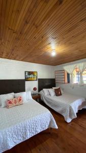 a bedroom with two beds and a wooden ceiling at Cerro Verde Salento in Salento