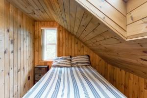a bedroom with a bed in a wooden room at Sheldrake Cove Retreat in Windham