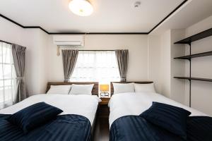 two beds in a small room with a window at Vacation Rental NISHIDA in Kagoshima
