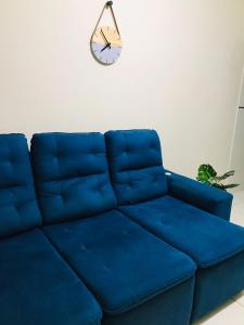 a blue couch in a room with a clock on the wall at Casa Aconchegante em Areia in Areia