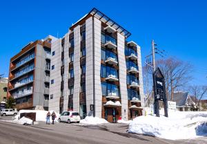 a building on a street with snow in front of it at Miru Nozomi Views in Kutchan