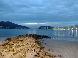 a large pile of rocks in the water with a city at Praia, sol e lazer in São Vicente