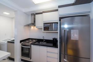 a kitchen with a stainless steel refrigerator and a stove at Cardeal 403C - Aconchegante apartamento na praia de Bombas - 2 dormitórios 5 pessoas - (Consultar serviços de roupa de cama e banho) in Bombas +7 photos