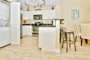 - une cuisine avec des placards blancs, une table et des chaises dans l'établissement Madeira Bay Resort 508, à St. Pete Beach